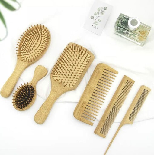 A photo of the 6 in 1 Wooden Natural Bamboo Detangling Hair Brush and Comb Set by BeaverStrong, with a person using the brushes and combs in the background.