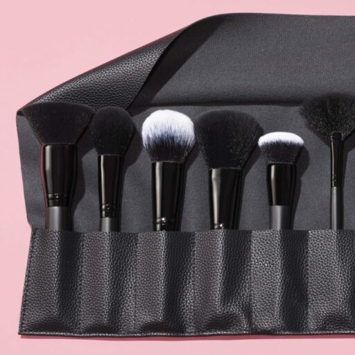 A few makeup brushes on a makeup table with a cleaning cloth in the background