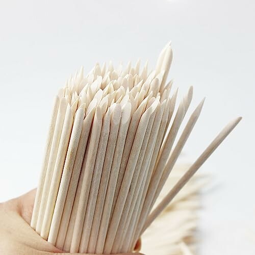 A hand holding bamboo cuticle sticks in a bundle.