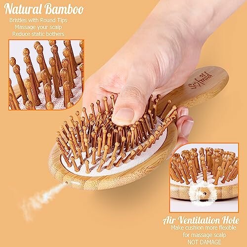 Hand holding bamboo hairbrush with round bristles and ventilation hole.