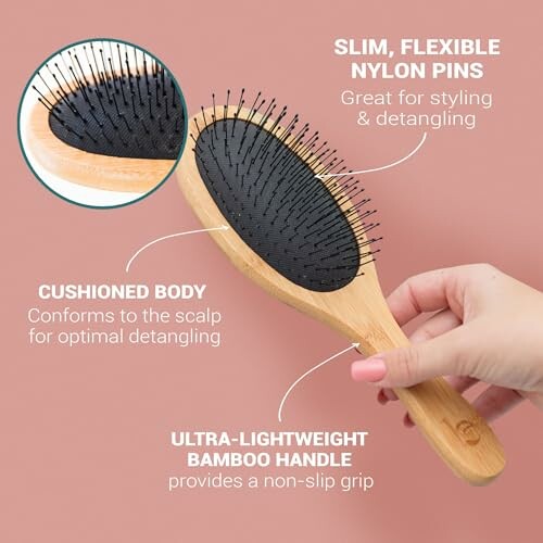 Hand holding a bamboo hairbrush with nylon pins and cushioned body.