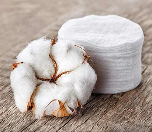 Cotton flower and cotton pads on wooden surface