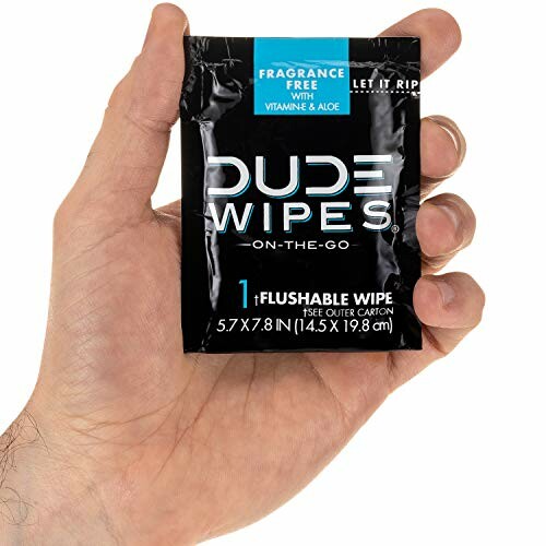 Hand holding a single pack of Dude Wipes, fragrance-free with vitamin E and aloe.