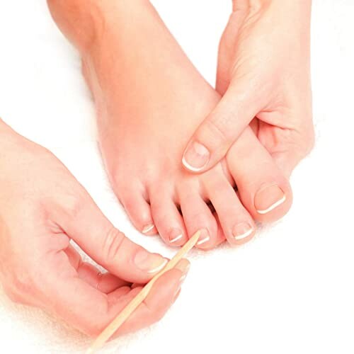 Person grooming toenails with a cuticle stick