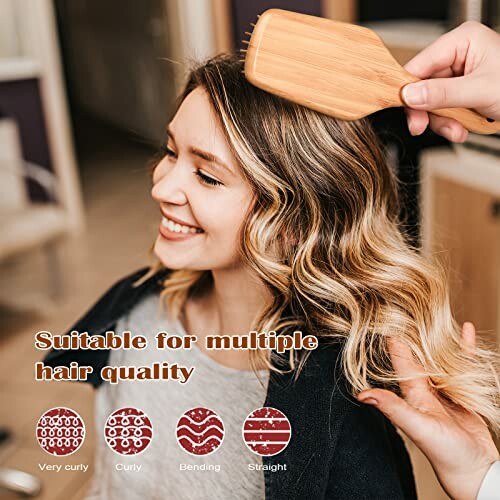 Person brushing woman's wavy hair with a wooden brush in a salon.