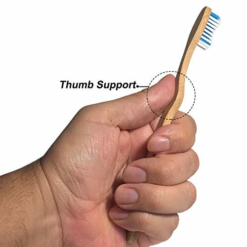 Hand holding a bamboo toothbrush with thumb support.