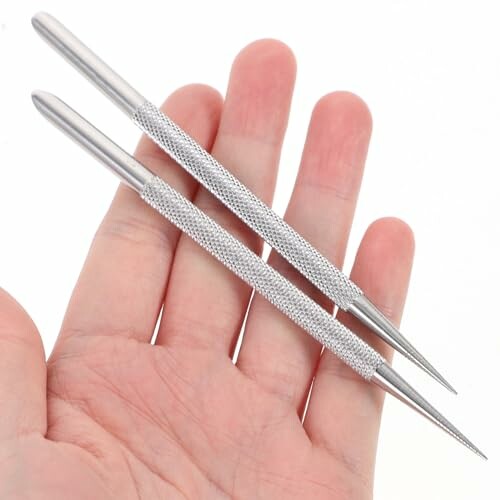 Hand holding two metal scribe tools with textured grips.