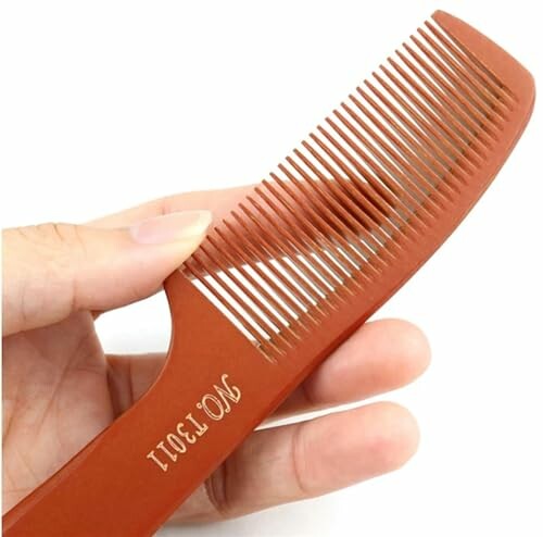 Hand holding a brown wooden comb.