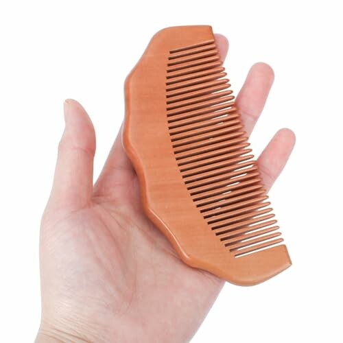 Hand holding a wooden comb.