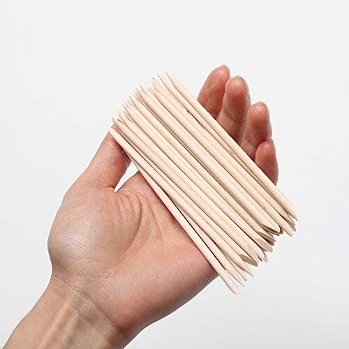 Hand holding a bunch of wooden sticks against a white background.