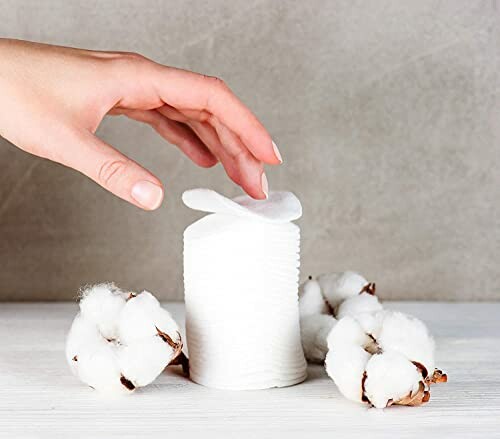 Hand reaching for cotton pads with cotton flowers