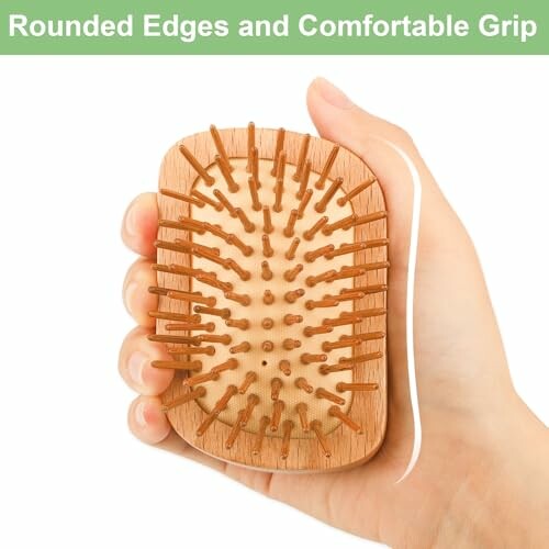 Hand holding a wooden hairbrush with rounded edges and comfortable grip.