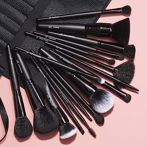 Set of various makeup brushes on a pink surface