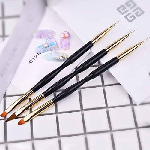 Set of three nail art brushes with gold and black handles on a tiled surface, alongside decorative nail designs.