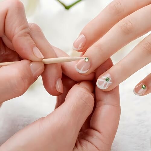 Close-up of hands applying nail art with gemstones