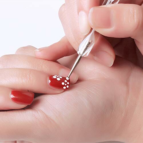 Close-up of hands creating red and white floral nail art.