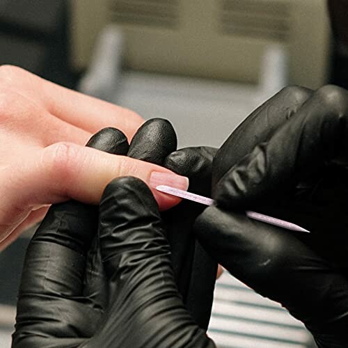 Manicure with black gloves shaping nails