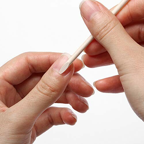 Hands using a wooden cuticle stick for nail care