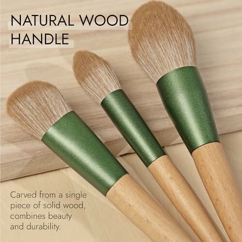 Three makeup brushes with natural wood handles and green metal ferrules.