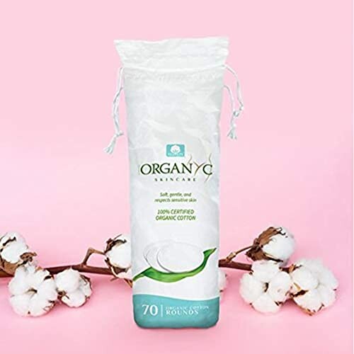 Pack of Organyc cotton rounds with cotton flowers on pink background.