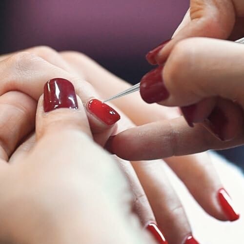 Close-up of a manicure process with red nail polish.