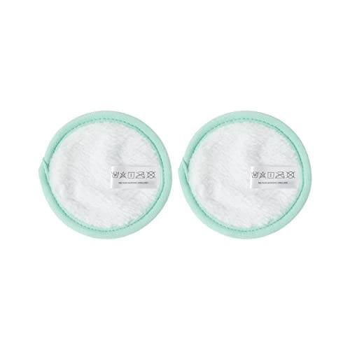 Two round reusable cotton pads with green edges.