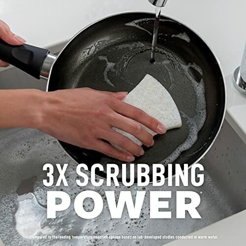 Person cleaning a frying pan with a sponge under running water.