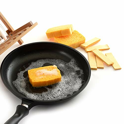 Sponge in a frying pan with soap suds, next to wooden rack and sponge strips.