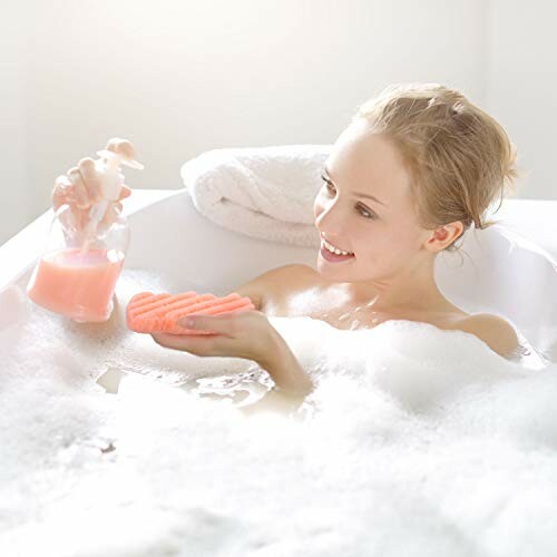 Woman smiling in a bubble bath holding soap.