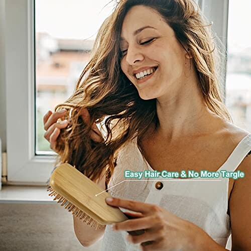 Woman smiling while brushing her hair near a window