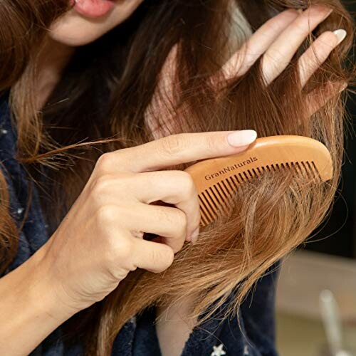 Woman combing hair with wooden comb