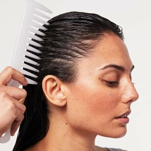 Woman combing wet hair with a wide-tooth comb.