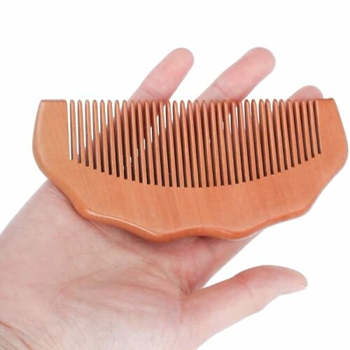 Hand holding a wooden beard comb