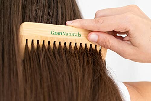 Person combing hair with a wooden GranNaturals comb