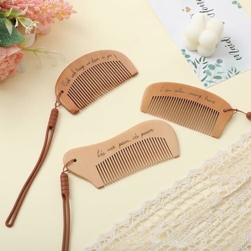 Three wooden combs with engraved quotes on a table.