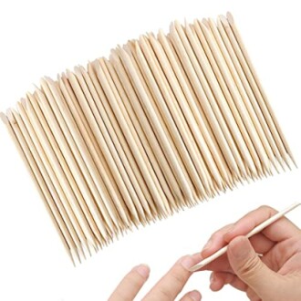 Wooden cuticle sticks being used on nails.