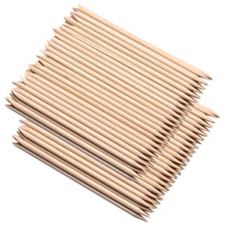 Pile of wooden cuticle sticks on white background