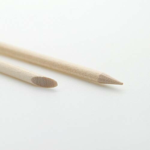 Two wooden cuticle sticks on a white surface.