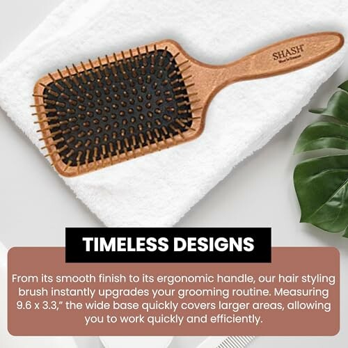 Wooden hairbrush on a white towel with plant nearby.