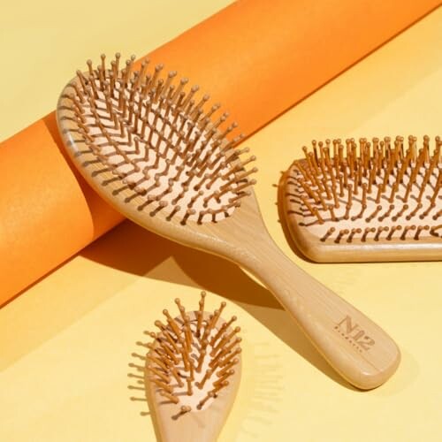 Three wooden hairbrushes on a yellow and orange background